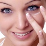 girl applying ointment to her eyes